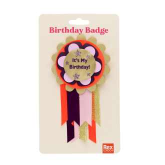 Colourful birthday badge with a gold centre reading ‘It’s My Birthday!’ and ribbons displayed with its packaging.