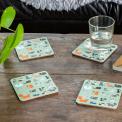 Four light green wood and cork coasters featuring cat pattern on table with drink