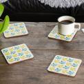 Four cream wood and cork coasters featuring bird pattern on table with drink