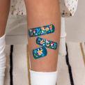 Dark blue plasters with print of fairies amongst flowers on child's leg