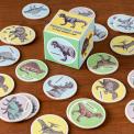 Memory game pieces with prints of pictures of dinosaurs on table with box