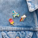 Roller skate, ice lolly and cloud burst pin badges attached to piece of clothing