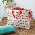 A large rectangular storage bag with red handles and a sausage dog pattern.