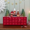 Red advent calendar with 24 gold-numbered drawers and a snowy village scene on top