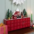 Red advent calendar with 24 gold-numbered drawers and a snowy village scene on top