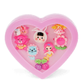 Assorted colourful rings with animal, mermaid, flower, and fruit designs in a pink heart-shaped box