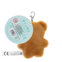 Light brown plush teddy bear keychain with a red polka-dotted bandana, metal clasp for attachment, and a tag with safety warnings