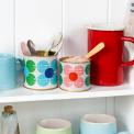 Mini daisy tins repurposed as kitchen storage on a shelf.