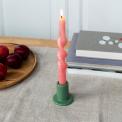 Khaki ceramic candle holder with a cylindrical shape and wide flat base, holding a lit pink candle