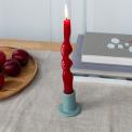grey ceramic candle holder with a cylindrical shape and wide flat base, holding a lit red candle