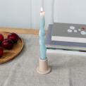 Taupe ceramic candle holder with a cylindrical shape and wide flat base, holding a lit candle