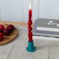 ceramic candle holder with a cylindrical shape and wide flat base, holding a lit red candle