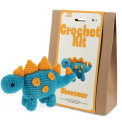 Blue crocheted dinosaur placed next to its packaging