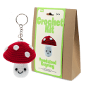 Crochet kit packaging displayed next to a finished red and white toadstool mushroom keychain
