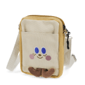 Beige and yellow crossbody bag with a front pocket featuring a smiling face design and two small brown plush feet at the bottom.