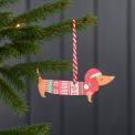 Wooden Christmas decoration of sausage dog wearing festive jumper and hat hanging on tree