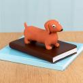 Squeezy squishy toy shaped like a brown sausage dog with floppy ears and a cute face placed on the book.