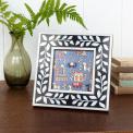 Square picture frame with white leaf patterns and navy blue colour on the border.