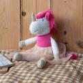 Knitted unicorn toy wearing a pink top and skirt