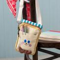 Beige and yellow crossbody bag with a front pocket featuring a smiling face design and two small brown plush feet at the bottom.