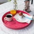 Round enamel trinket tray in vibrant pink displayed with cup of coffee, orange juice and egg.