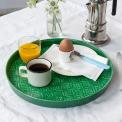 Round enamel trinket tray in dark green displayed with cup of coffee, orange juice and egg.