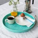 Round enamel trinket tray in aqua displayed with cup of coffee, orange juice and an egg.