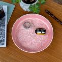 enamel trinket dish in pink displayed with a camera film roll.