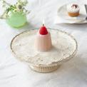Pink jelly-shaped candle topped with a decorative red strawberry displayed on a decorative cake stand.