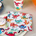 Dinosaur‑themed party paper napkin with matching paper plate and cup beside it.