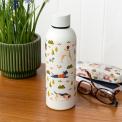 Stainless steel bottle with playful dog illustrations on a table beside a matching glasses case.