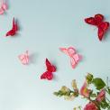 A string garland decorated with colourful feather butterflies hanging against a light background.