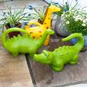 Brightly coloured animal‑shaped watering cans, including a dinosaur, giraffe and crocodile.
