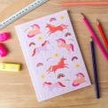 Pink notebook with colourful unicorns, rainbows, stars, and suns on the cover.