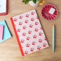 Pink notebook with cherry design on the cover.