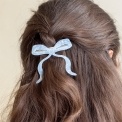 Hair clip featuring a pretty bow design in blue, with hints of marbling and translucence. 