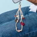 Beige cord phone strap with decorative flower and bead charms shown attached to a phone.