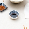 Round ceramic dipping bowl with blue line pattern shown with soy sauce.