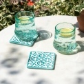 Turquoise ceramic tile coasters with white pattern beside two glasses of lemon water.