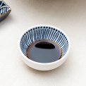 Round ceramic dipping bowl with blue line pattern shown with soy sauce.