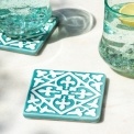 Turquoise ceramic tile coasters with white pattern beside two glasses of lemon water.
