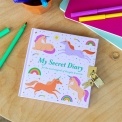 Unicorn-themed secret diary with padlock and keys on a desk with colourful stationery.