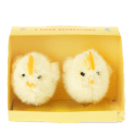 Two fluffy yellow chick decorations sitting side by side inside a small yellow cardboard box