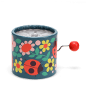 Winding music box with illustrated flowers and ladybird design, featuring a red turning handle.