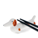 Chopsticks resting on a ceramic sausage dog–shaped chopstick rest.
