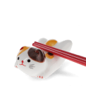 Chopsticks resting on a ceramic cat–shaped chopstick rest.