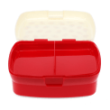 Open red lunch box with a cream lid and two interior compartments tray.