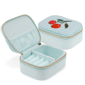 Open light blue jewellery box with embroidered cherry design, ring rolls and storage compartments.