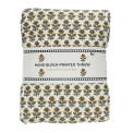 Hand block-printed throw with yellow floral pattern, folded in packaging.
