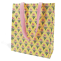 Yellow shopping bag with floral block-print pattern and matching pink carry handles.